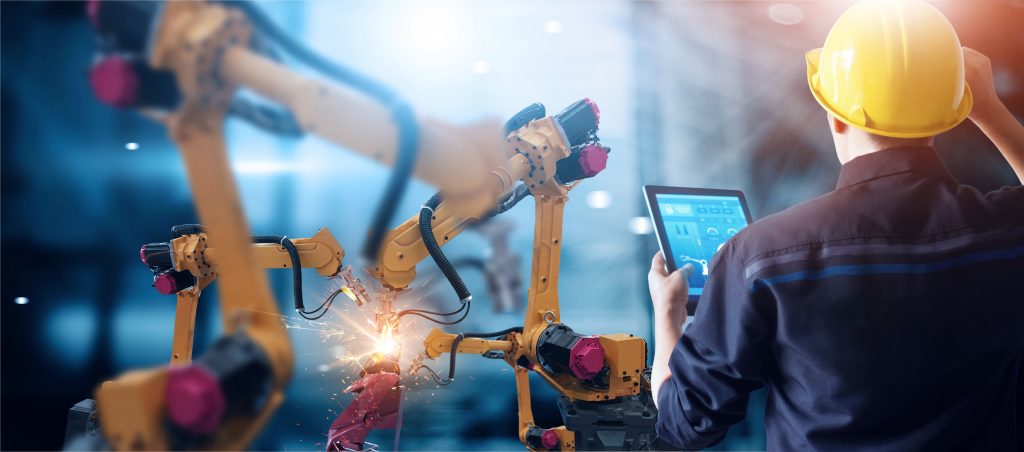 Industry 4.0 Worker with Hard Hat and Tablet Computer Looking at Yellow Robot